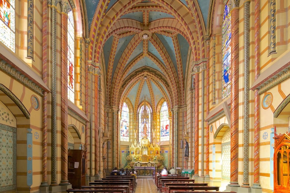 A cathedral interior with high vaulted ceilings, stained glass windows, and ornate columns.