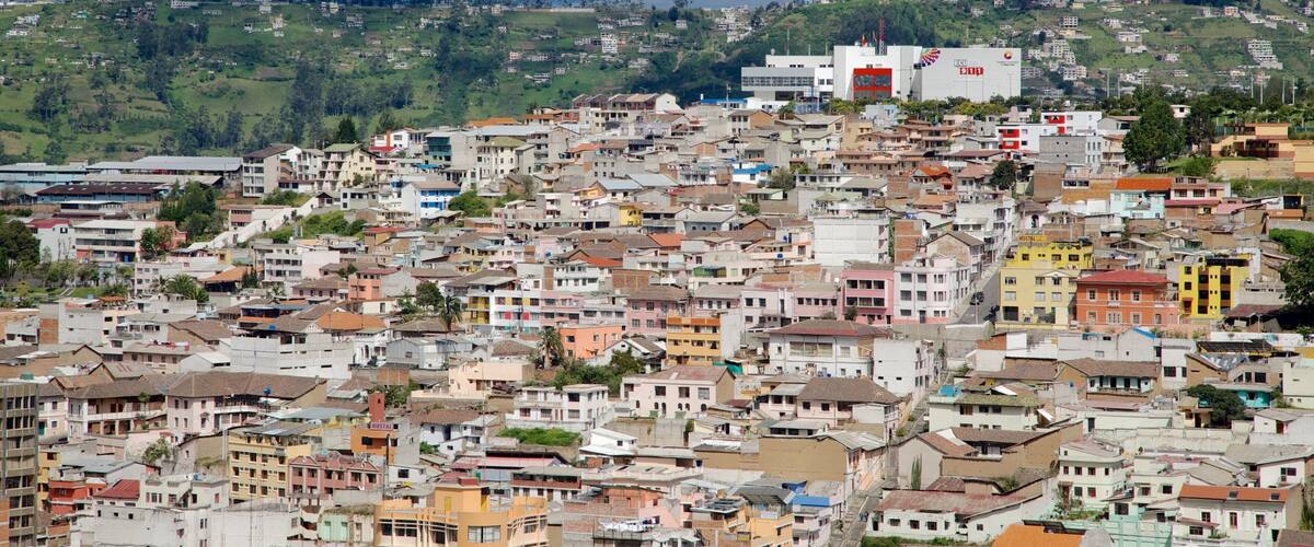 A densely packed hillside town with colorful buildings and a prominent red and white structure in the background.