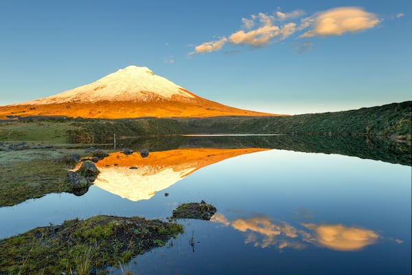 A breathtaking view of the snow-capped Cotopaxi volcano in Ecuador's Parque Nacional Cotopaxi, with Laguna de Santo Domingo in the foreground.