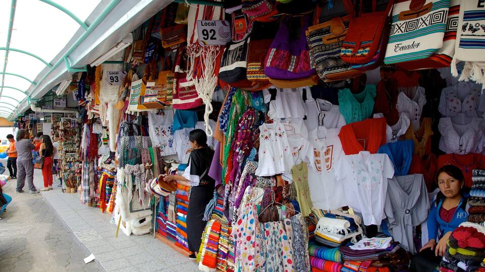 Un étal de marché proposant des textiles et des vêtements aux couleurs vives.