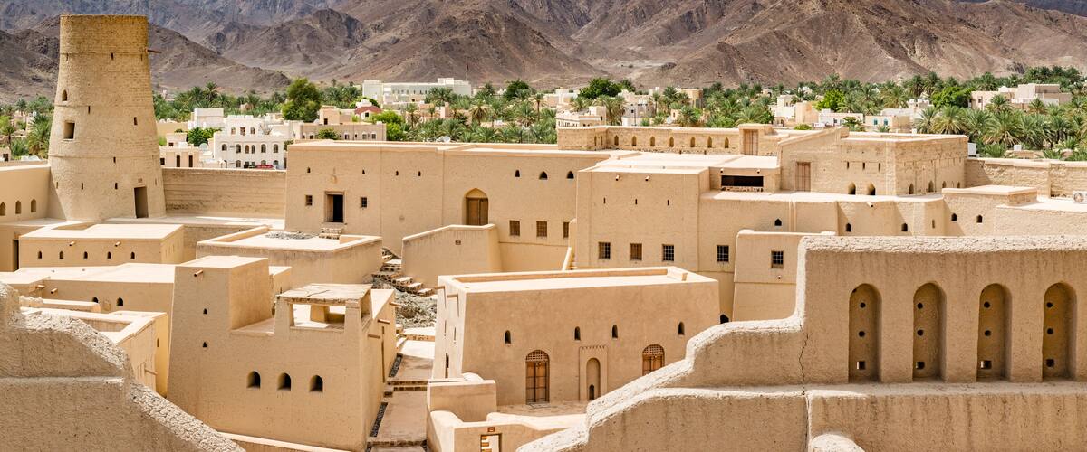 A desert town with traditional architecture, mountains in the background, and a clear sky.