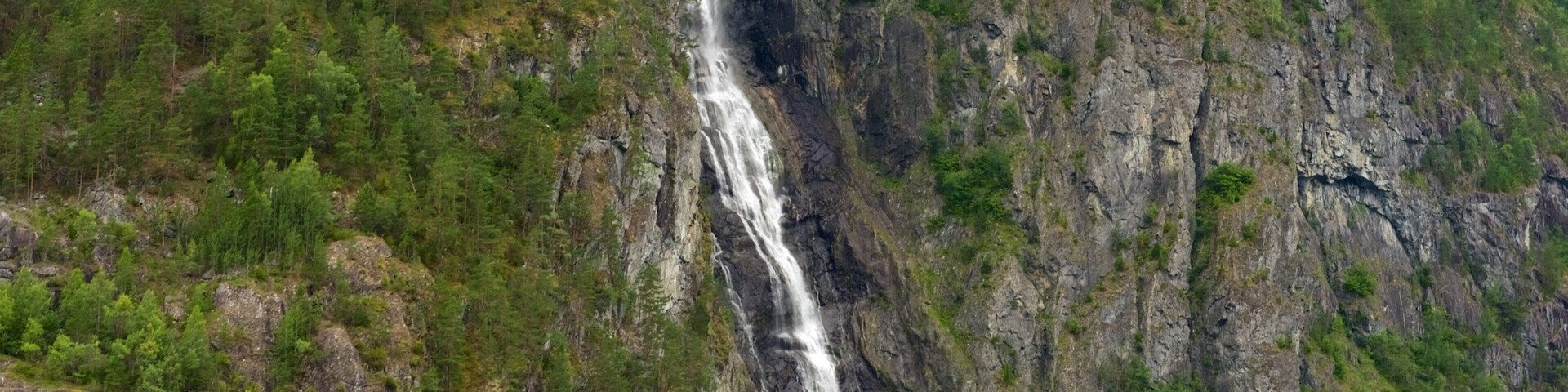 A waterfall cascading down a rocky cliff surrounded by dense green forest.