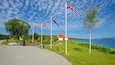 En kustväg med flaggor, ett vitt hus och en sjö.