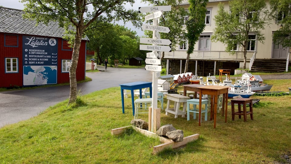 A signpost with directions to various locations, a red building with a map, and outdoor furniture.