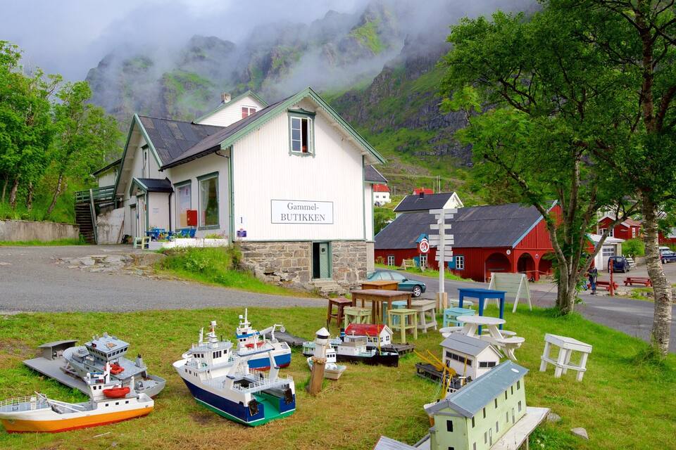 A coastal village with a white building labeled "Gammel-BUTIKKEN" surrounded by model boats and a mountainous backdrop.