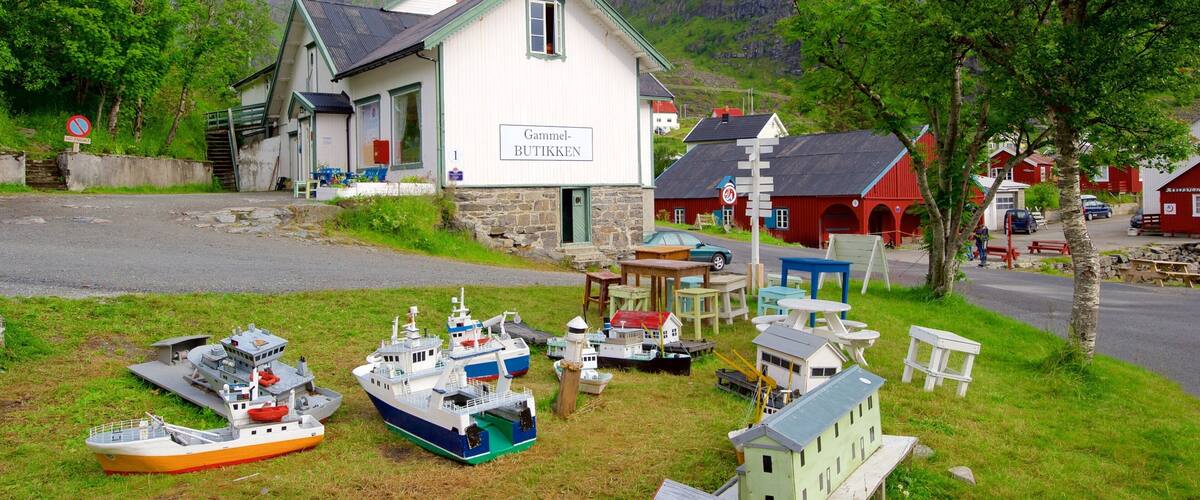 A coastal village with a white building labeled "Gammel-BUTIKKEN" surrounded by model boats and a mountainous backdrop.