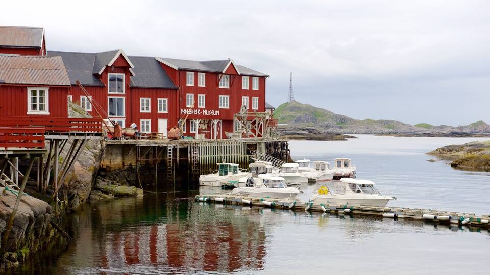 A red building with a sign reading "Kleivfjord Museum" and boats docked in the water.