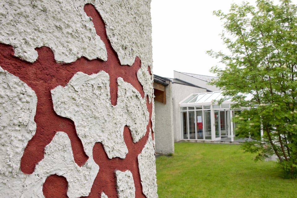 A building with a unique red and white facade and a green tree in the foreground.
