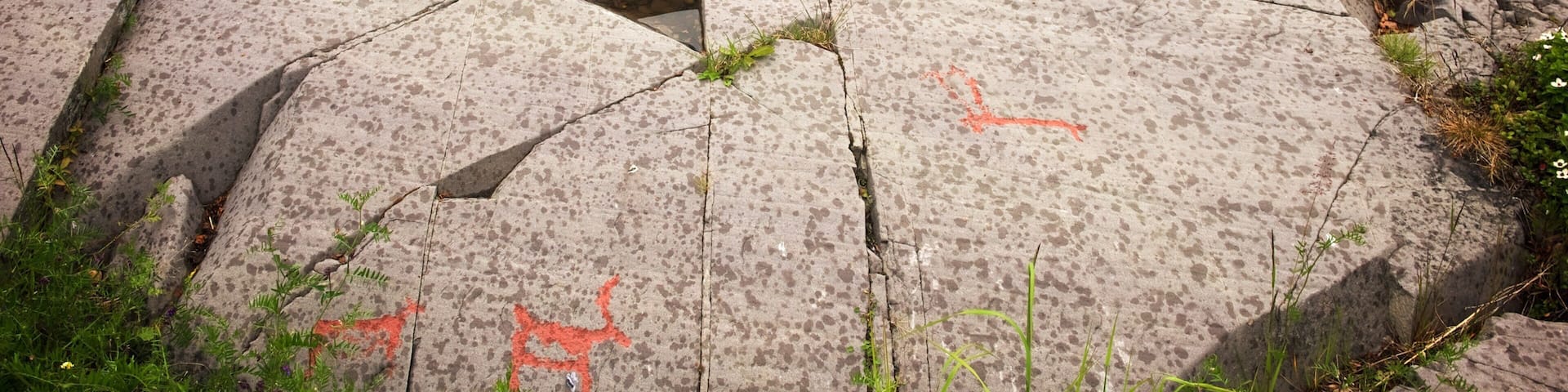 A large, cracked stone pavement with red graffiti.