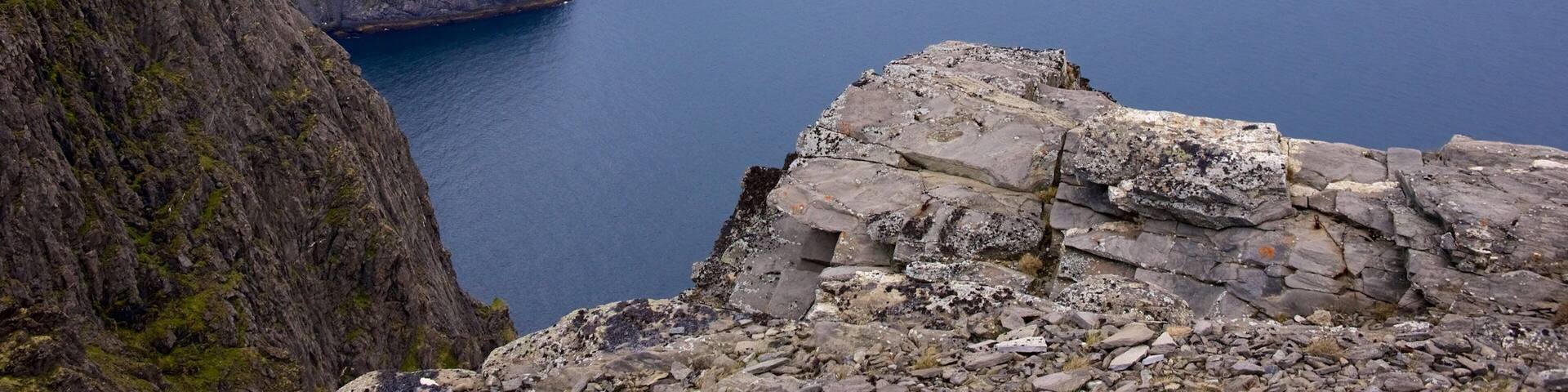 A rugged coastline with steep cliffs and a calm sea.