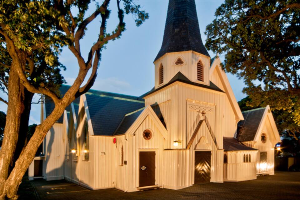 Uma igreja com uma torre alta e uma cruz na fachada.