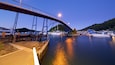 A bridge over a calm river with boats docked on the right.