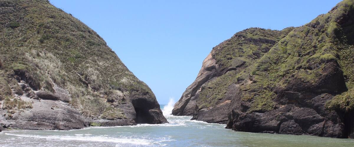 A narrow canyon with steep rock walls and a river flowing through it.