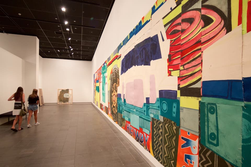 An art gallery with a large colorful mural on the wall.