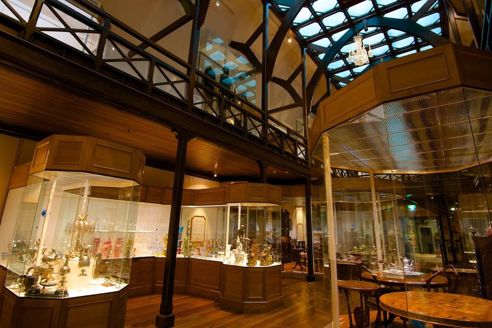 Interior de museu com vitrines de vidro exibindo diversos artefatos.