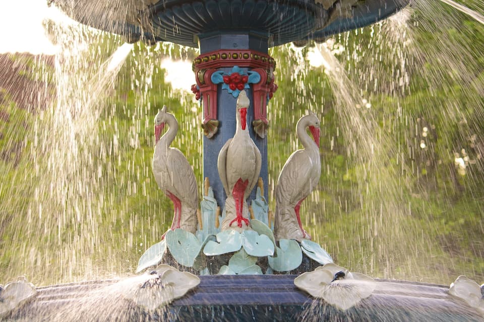 A fountain with three swans and water spouting from the top.