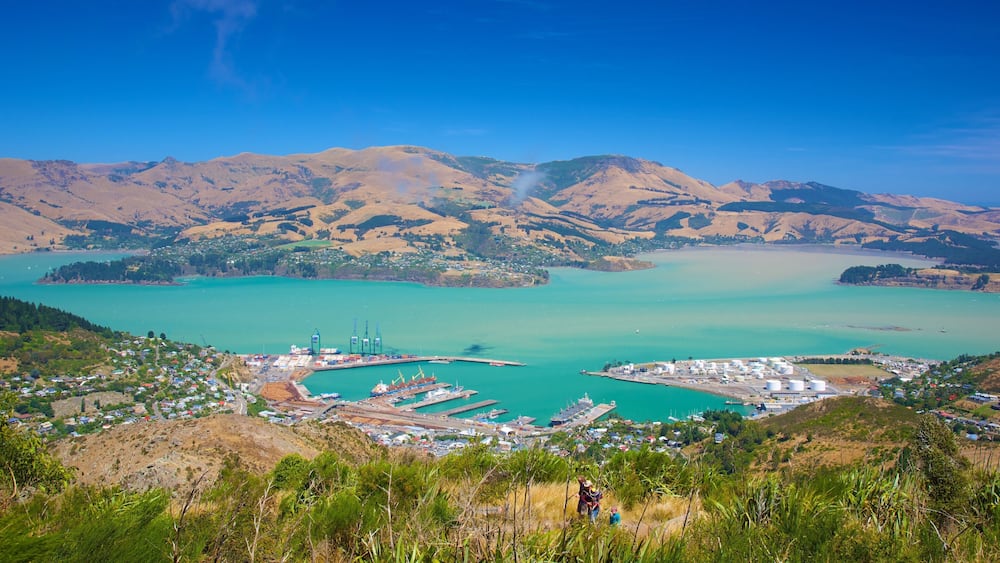 A coastal town with a harbor, mountains in the background, and a clear blue sky.