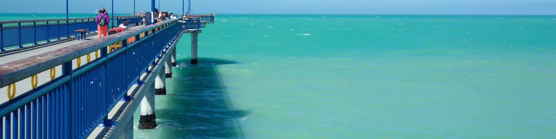 Un muelle se adentra en aguas turquesas bajo cielos despejados.