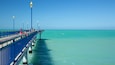 A pier extending into turquoise waters with clear skies.