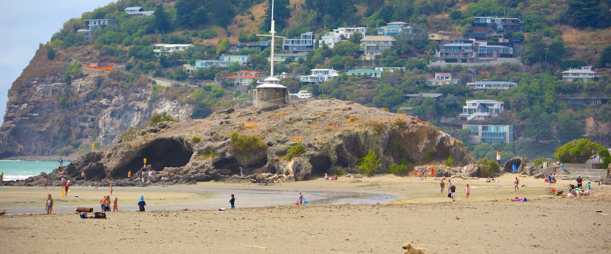 Cave Rock showing caves, a sandy beach and a coastal town