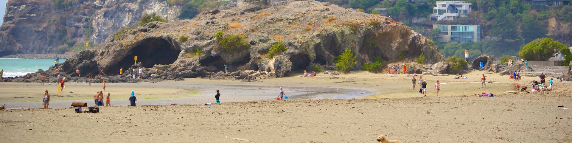 Cave Rock showing caves, a sandy beach and a coastal town