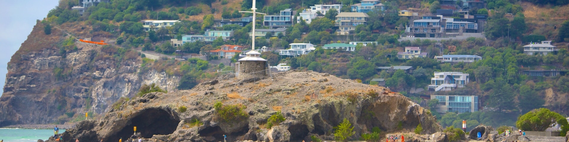 Cave Rock showing caves, a sandy beach and a coastal town