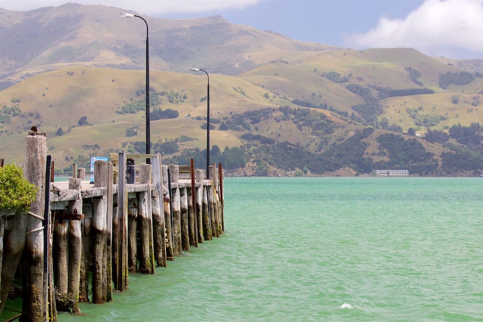 A wooden pier extending into turquoise water, with mountains in the background.