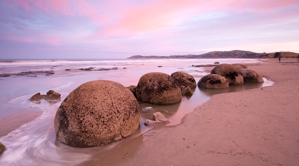 Moeraki Boulders showing rugged coastline, a sunset and a sandy beach