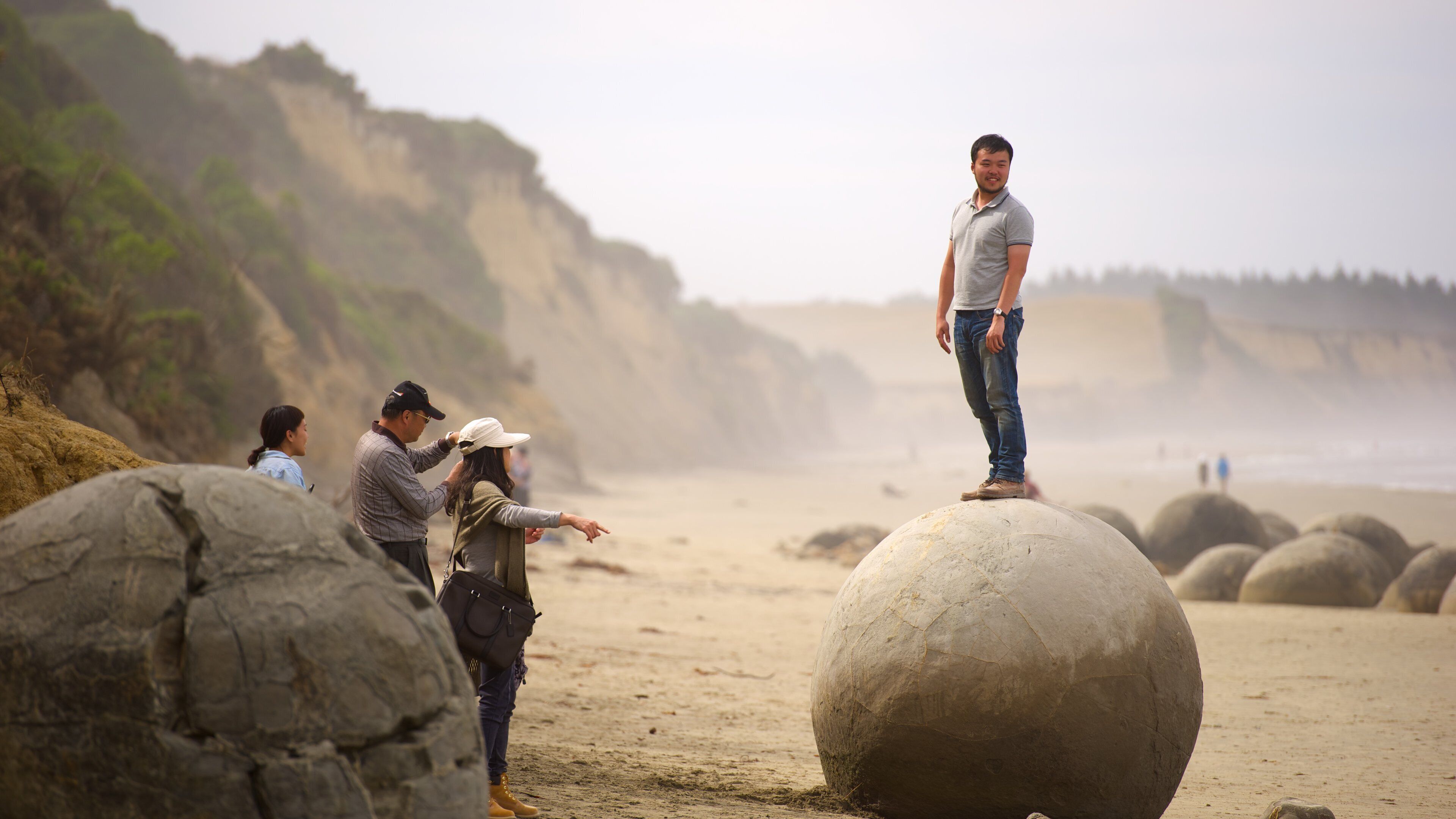 Moeraki Boulders which includes rugged coastline as well as a small group of people