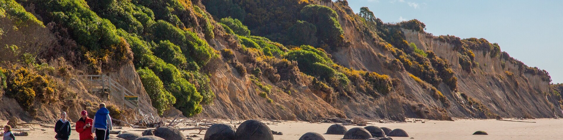 Moeraki Boulders which includes a beach as well as a small group of people