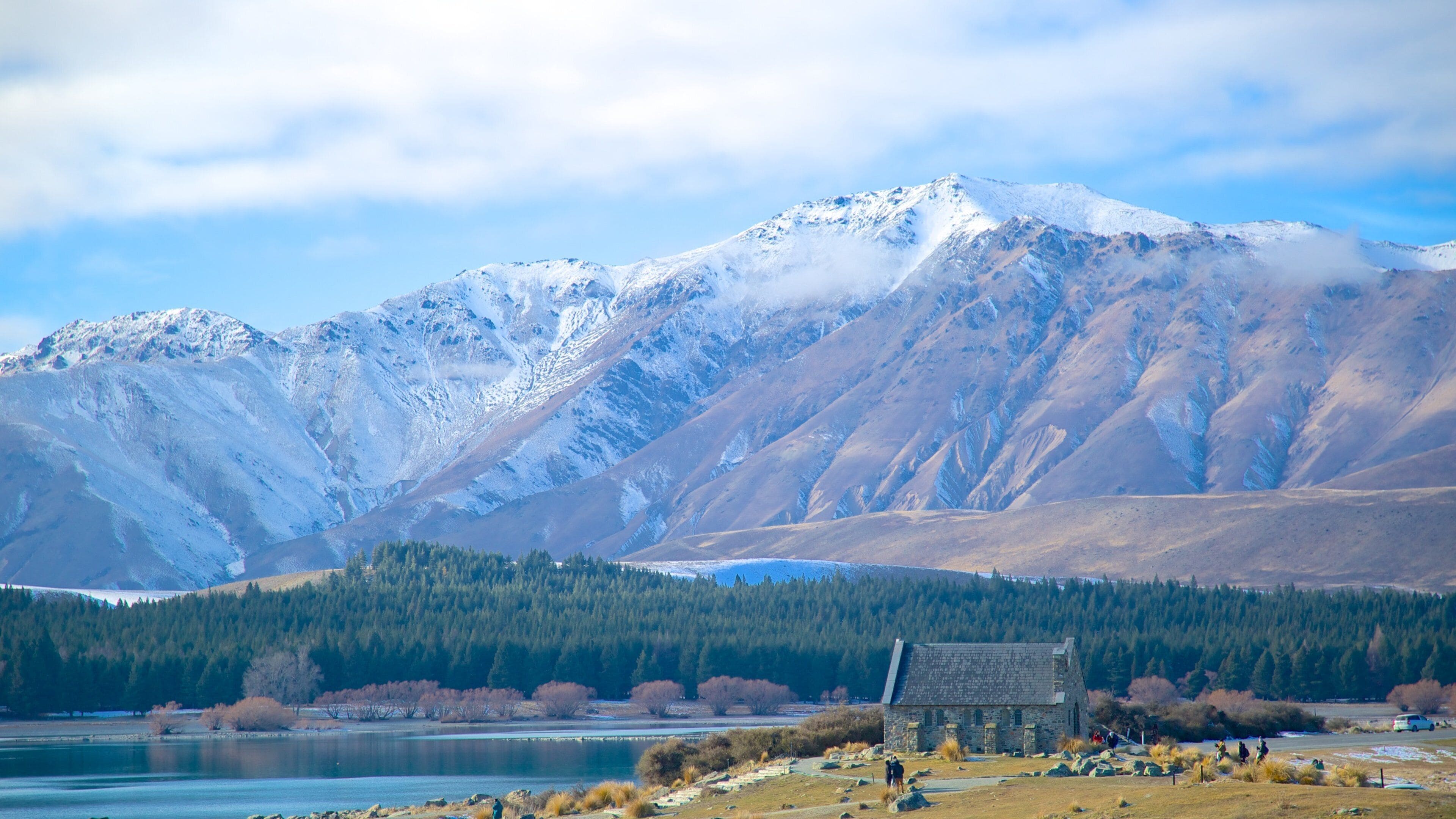 Una cordillera con un lago y un edificio de piedra al frente.