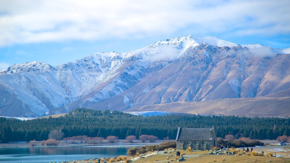 A mountain range with a lake and a stone building in the foreground.