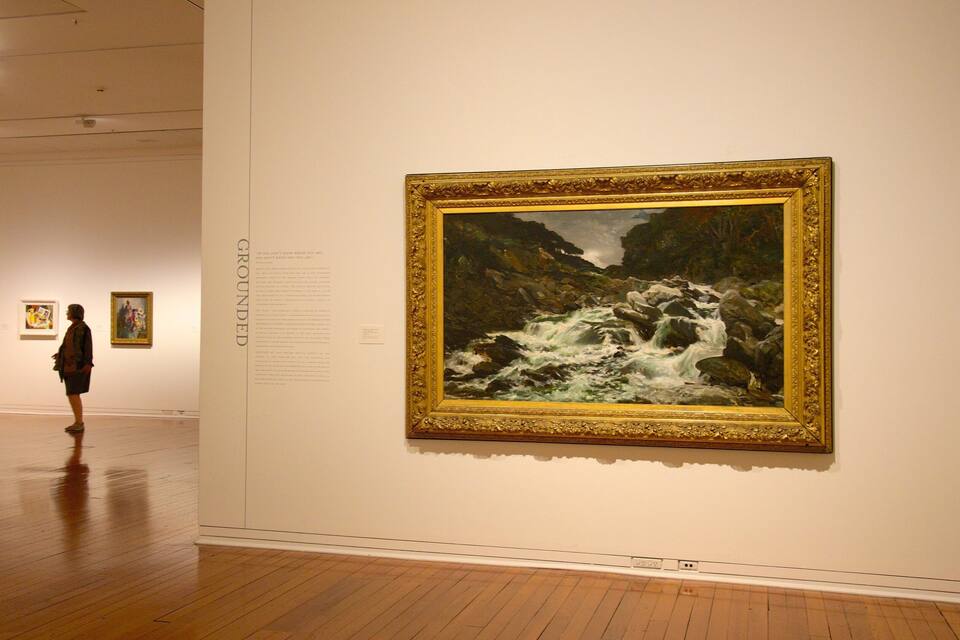 Una galería de arte con un cuadro grande de un paisaje fluvial en la pared.