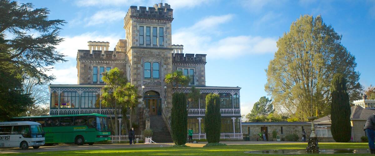 A historic building with a tower, surrounded by trees and a green bus.