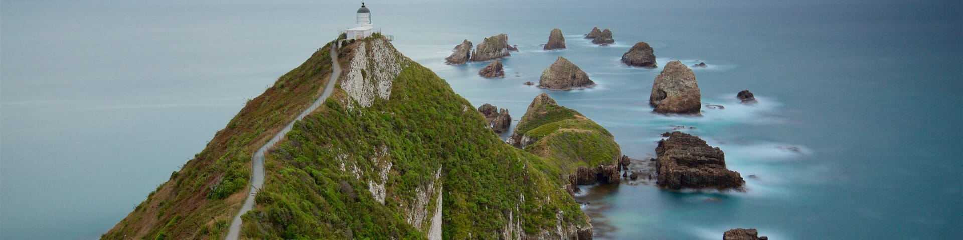 Nugget Point Lighthouse featuring mist or fog, rocky coastline and a bay or harbor
