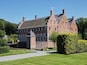 A large brick building with multiple chimneys and a prominent tower.