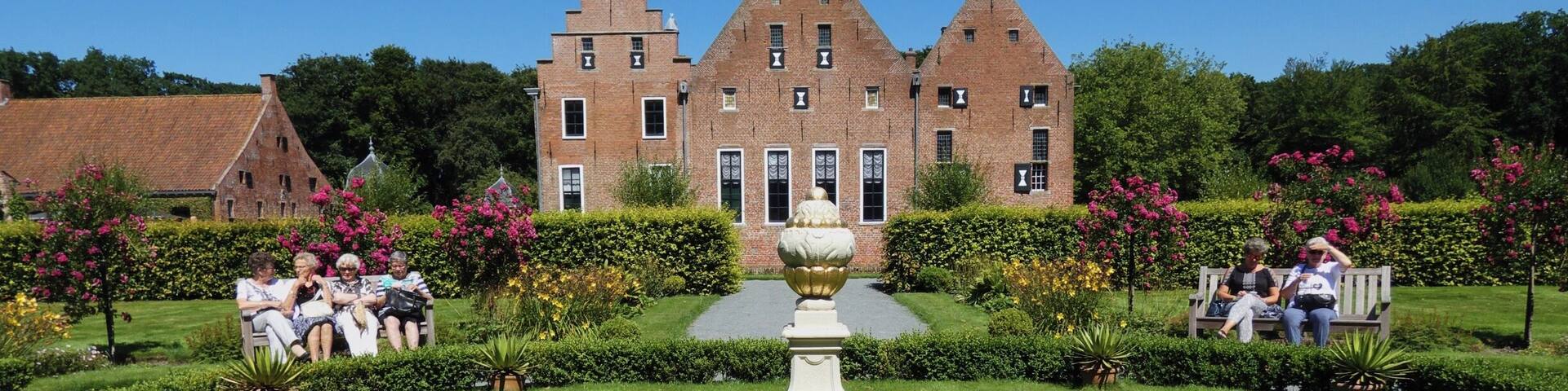 A large brick building with a symmetrical garden and a central fountain.