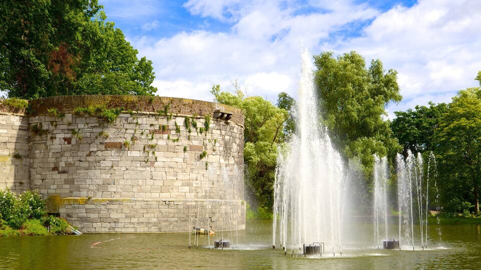 A stone wall with a fountain in a park.