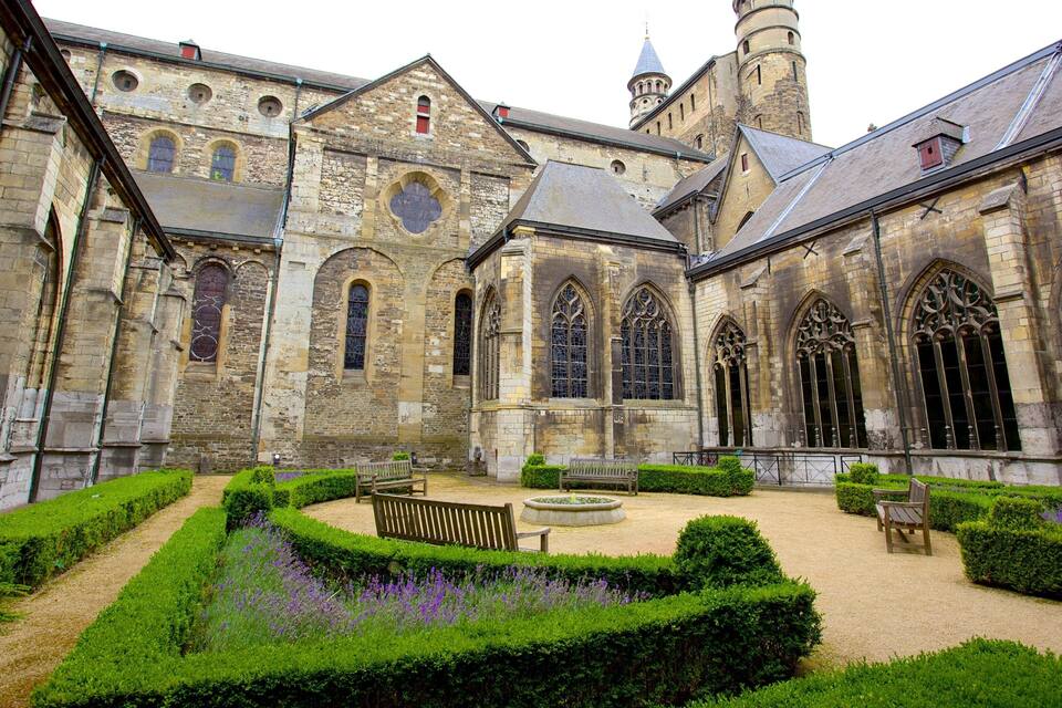 A historic cloister with stone buildings, arched windows, and a tower.