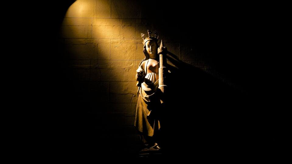 A statue in a dimly lit room with a brick wall.