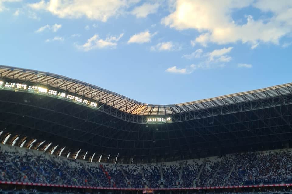 A large stadium with a curved roof and multiple tiers of seating.