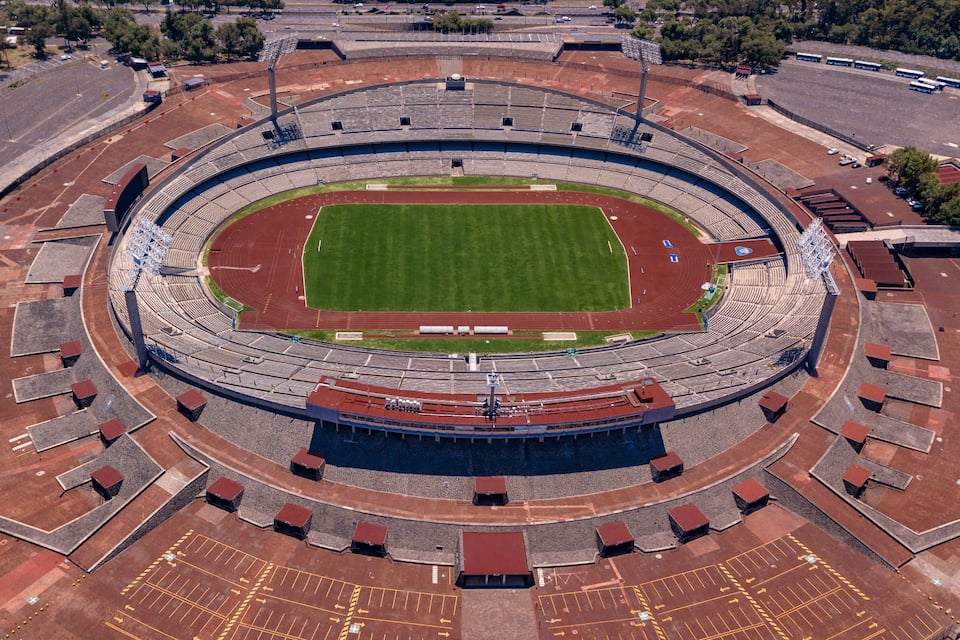 An empty stadium with a central field and surrounding seating.