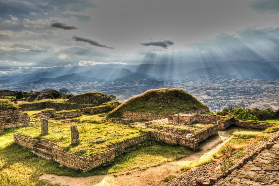 Ruinas antiguas con vistas a montañas lejanas y un cielo nublado.