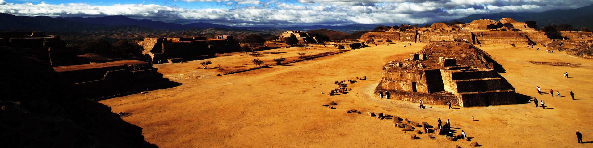 A large ancient pyramid complex with multiple structures and a clear blue sky.