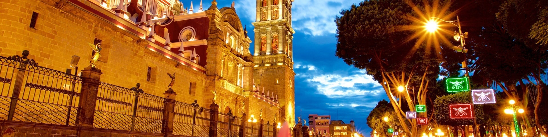 Um edifício histórico com uma torre de sino e uma cúpula, iluminado ao entardecer.
