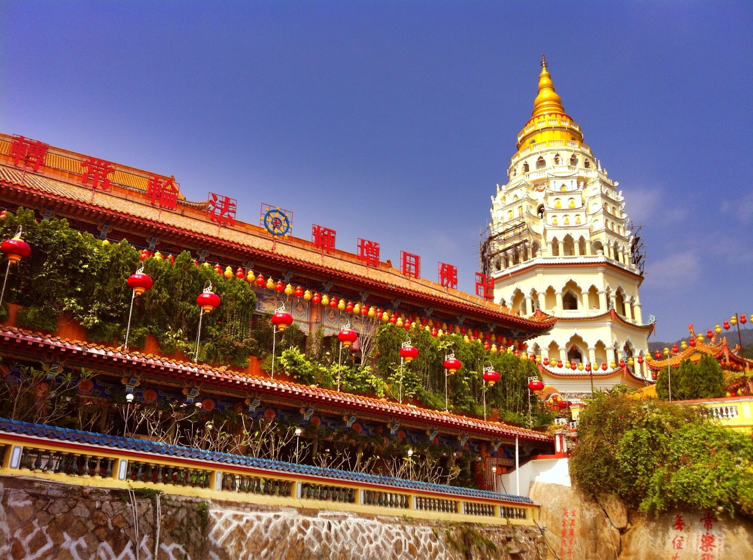 A traditional temple with a golden spire, red lanterns, and intricate architecture.
