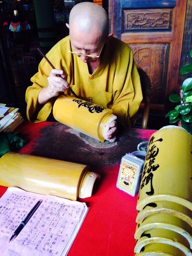 A Chinese monk paints fine calligraphy on bamboo tiles at the Kek Lok Si temple