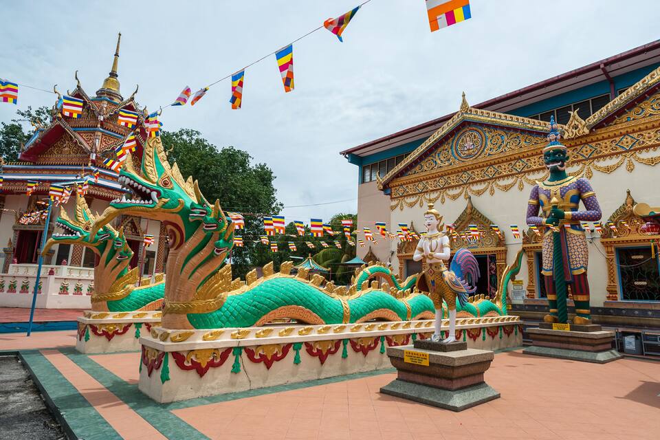A temple with ornate architecture, including a dragon statue and a seated figure.