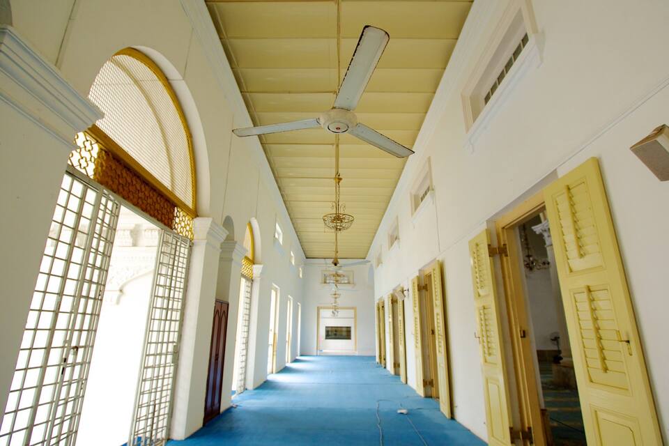 A long corridor with a blue floor, white walls, and yellow doors.