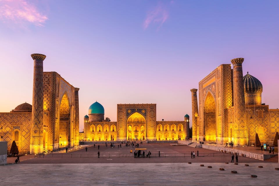 A historic building with intricate patterns and domes, surrounded by a spacious courtyard.